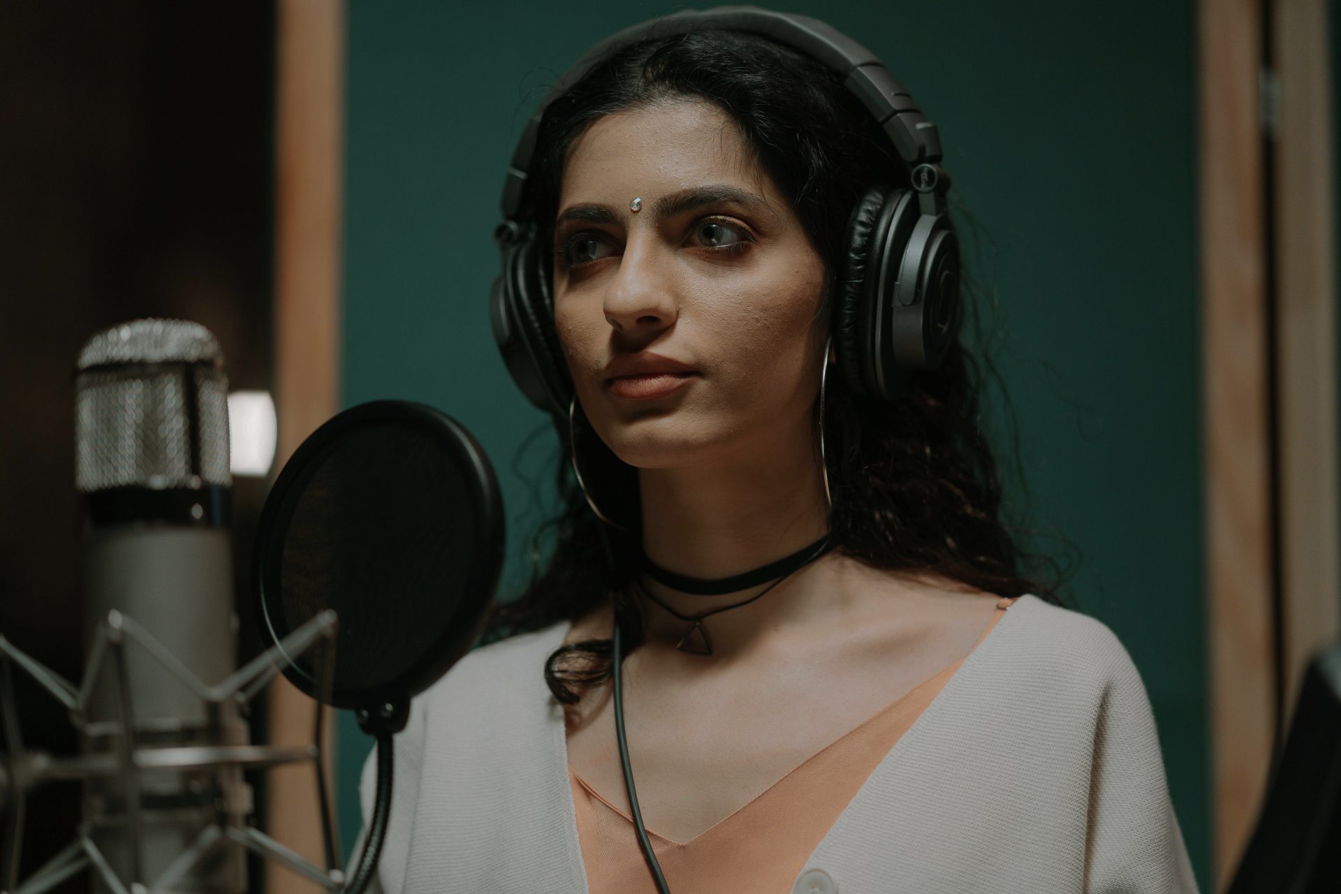 pexels-cottonbro-7087168 (1) - Edited Female voice over artist in a recording booth, with a microphone in front of her.