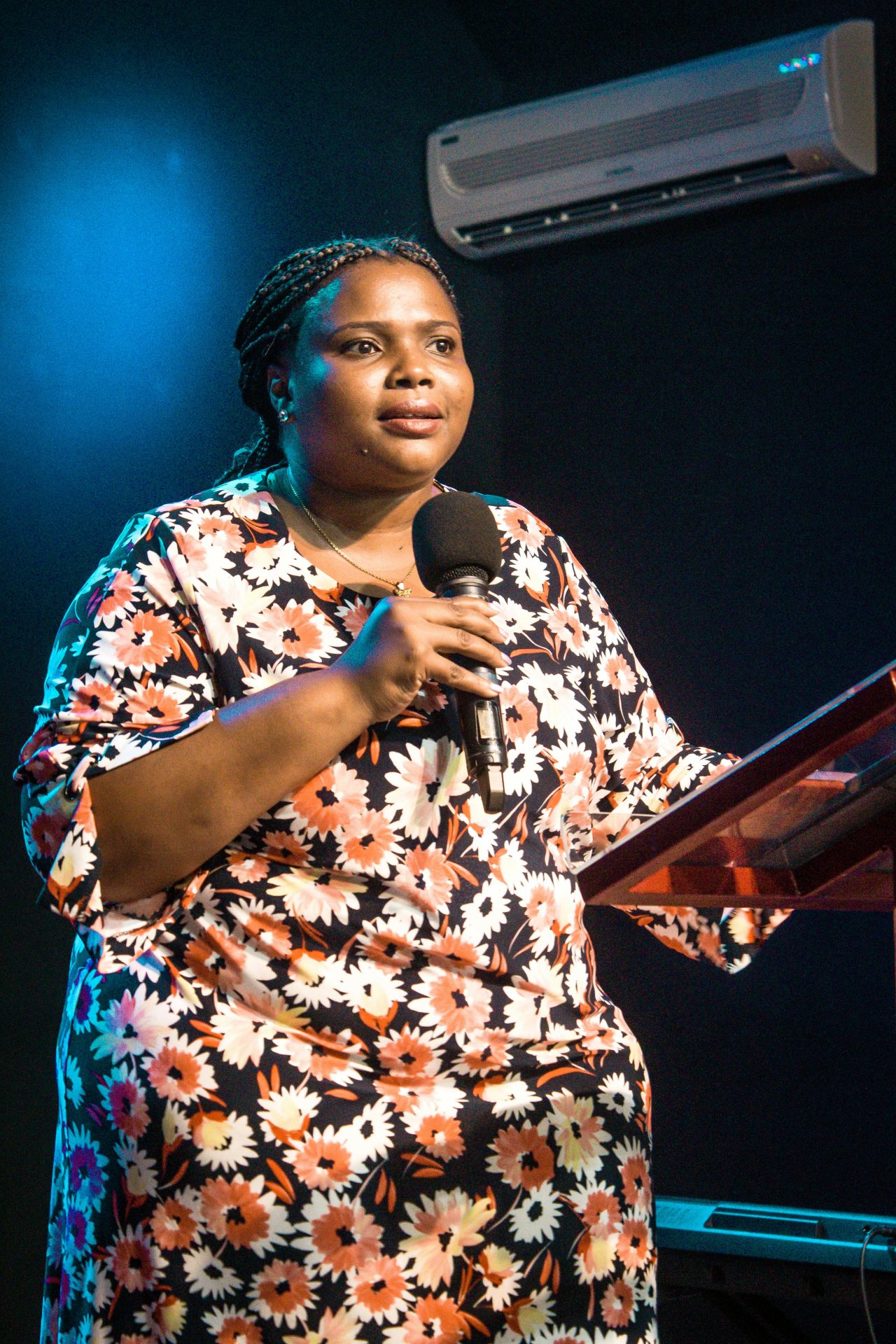 pexels-su-casa-panama-56317556-10035603 A woman in a floral dress is stood up with a microphone