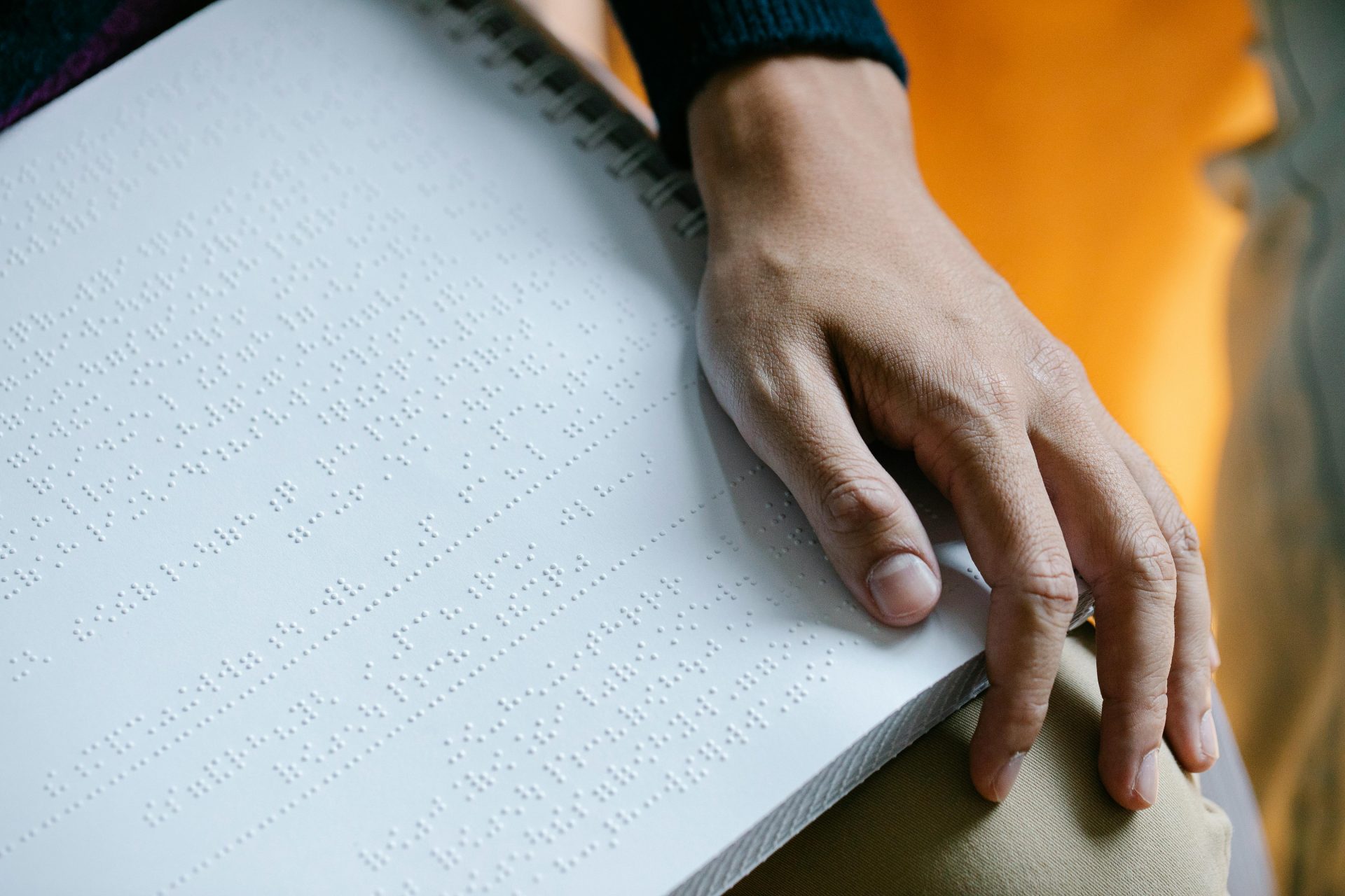 A thumb is going over braille on a notepad